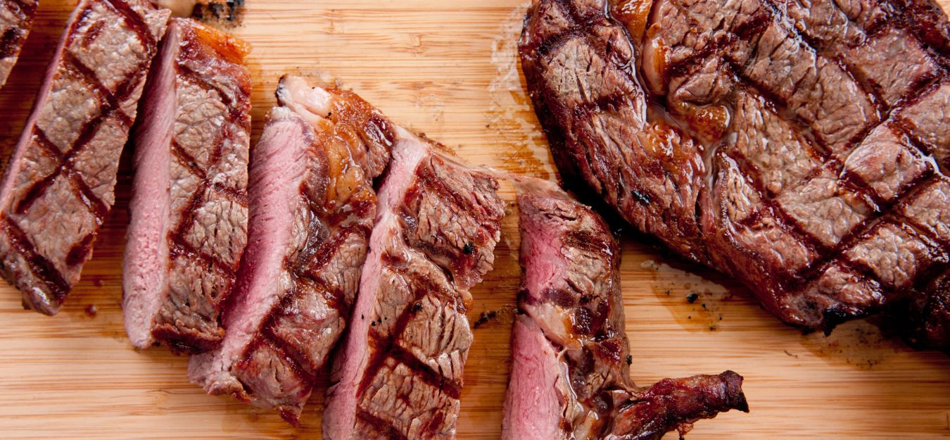 A medium-rare steak sliced up on a cutting board.